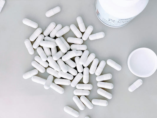 White capsules on a flat surface near a white bottle